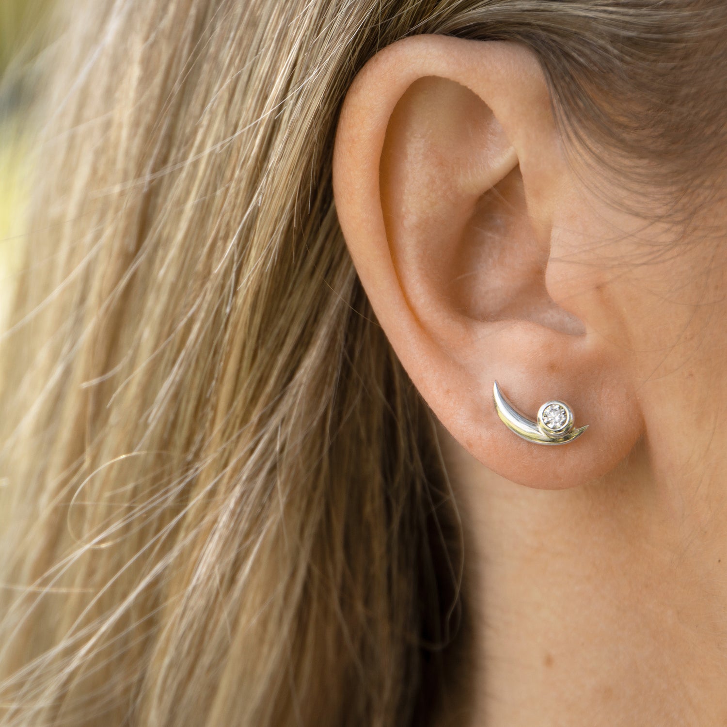 Solid white gold bezel set diamond earring on the ear